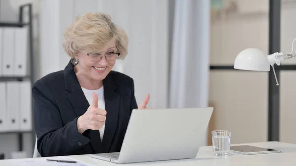 Vieille femme d'affaires célébrant le succès tout en utilisant un ordinateur portable — Photo