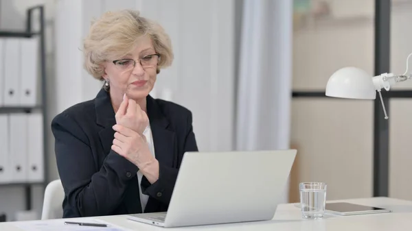 Alte Geschäftsfrau hat Handgelenkschmerzen bei der Arbeit am Laptop — Stockfoto