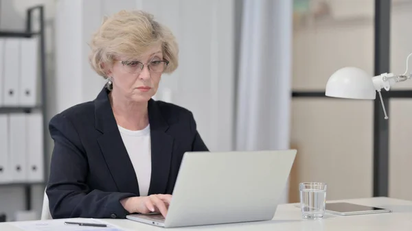 Vieille femme d'affaires utilisant un ordinateur portable au travail — Photo