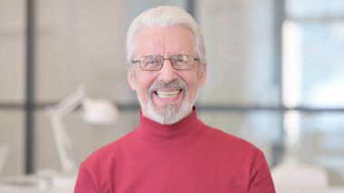 Yaşlı adam kameraya gülümsüyor. 