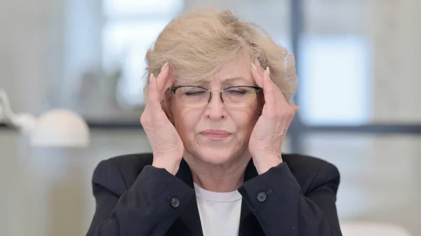 Vecchia donna d'affari che ha mal di testa al lavoro — Foto Stock