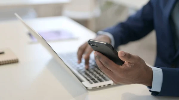 Uomo d'affari africano che utilizza laptop e smartphone, Close up — Foto Stock