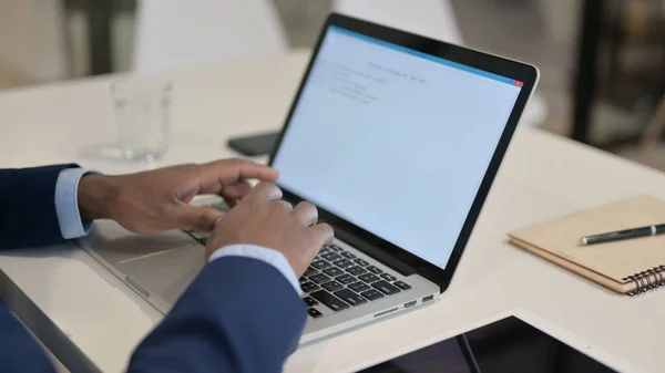 Afrikanischer Geschäftsmann tippt im Büro auf Laptop aus nächster Nähe — Stockfoto