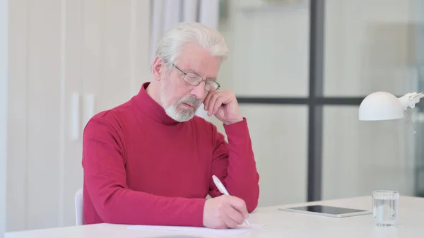 Vieil homme écrivant sur le papier au travail — Photo