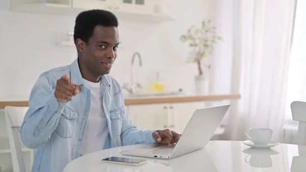 Afričan s laptopem ukazujícím na kameru — Stock fotografie