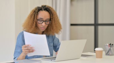 Dizüstü bilgisayar üzerinde çalışırken Afrikalı Kadın Belgeleri Okuyor 