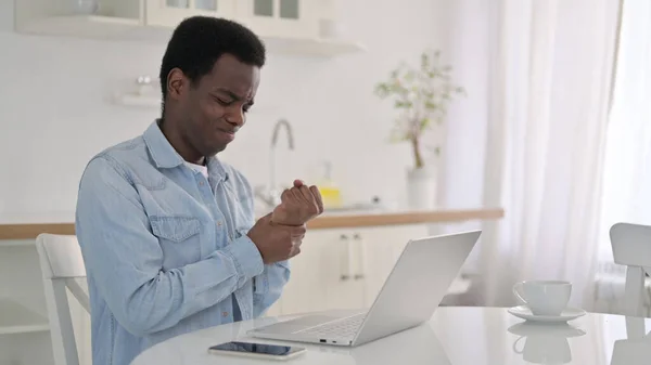 Homme africain avec ordinateur portable ayant la douleur au poignet à la maison — Photo