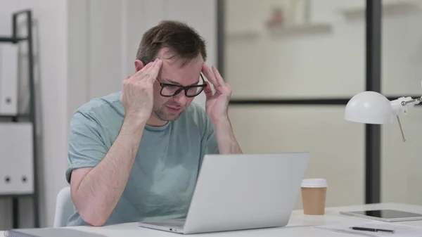 Jongeman heeft hoofdpijn tijdens het werken op laptop — Stockfoto