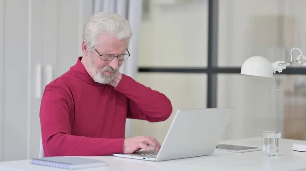 Old Man having Neck Pain while working on Laptop