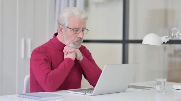 Vieil homme pensant tout en travaillant sur ordinateur portable — Photo