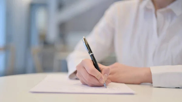 Primer plano de la mujer escribiendo en papel en el café —  Fotos de Stock