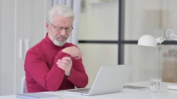 Old Man having Wrist Pain while working on Laptop