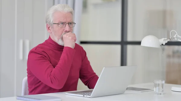 Vieil homme ayant la toux tout en travaillant sur ordinateur portable — Photo