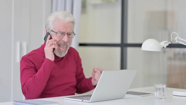 Old Man with Laptop Angry on Smartphone