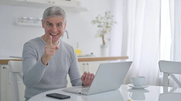 Positiver alter Mann mit Laptop zeigt Ja-Zeichen mit Finger — Stockfoto