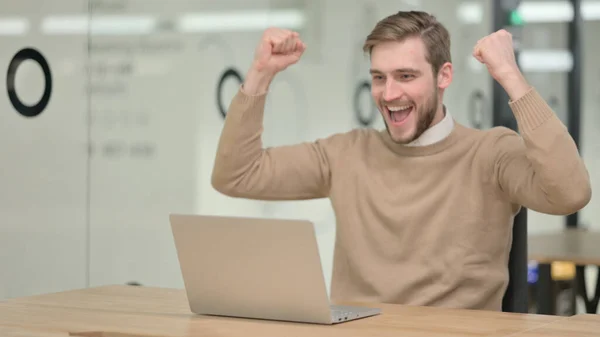 Junger Mann mit Laptop feiert im Büro — Stockfoto