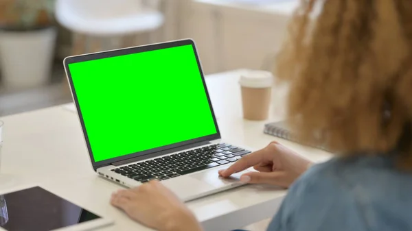 Vista trasera de la mujer africana usando el ordenador portátil con la pantalla dominante verde del croma —  Fotos de Stock