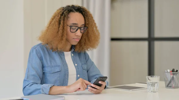 Africká žena pomocí chytrého telefonu v práci — Stock fotografie