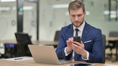 İş yerinde Smartphone kullanan İşadamı