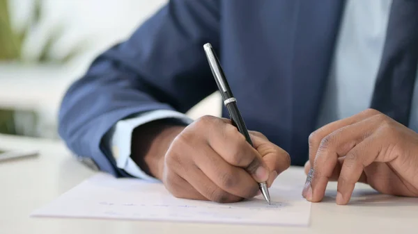 Empresario africano escribiendo sobre papel — Foto de Stock