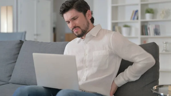 Человек работает на ноутбуке с болями в спине дома — стоковое фото