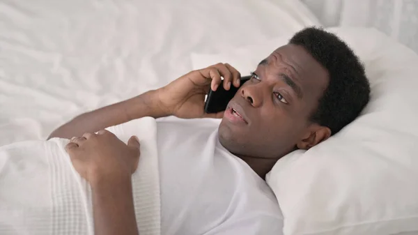 African Man Mówienie przez telefon w łóżku — Zdjęcie stockowe