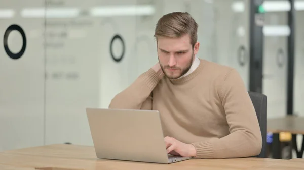 Giovane con computer portatile con dolore al collo in ufficio — Foto Stock