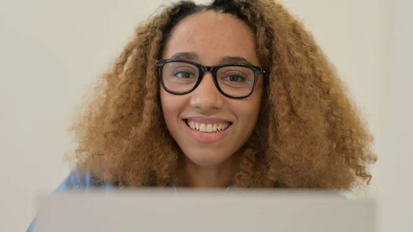 Retrato de mulher africana sorrindo para a câmera ao usar o laptop — Fotografia de Stock