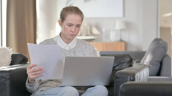 Женщина работает на ноутбуке с документами дома — стоковое фото