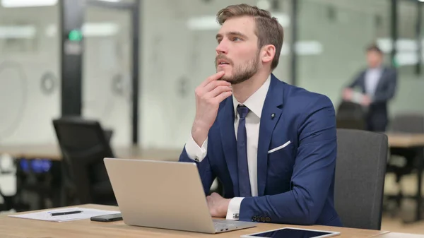 Empresario con el pensamiento del ordenador portátil en el trabajo — Foto de Stock