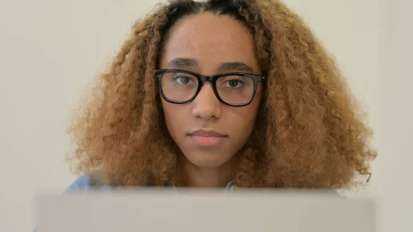 Retrato da mulher africana olhando para a câmera ao usar o laptop — Fotografia de Stock