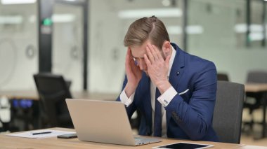 Başağrısı olan bir iş adamı Laptop üzerinde çalışıyor 
