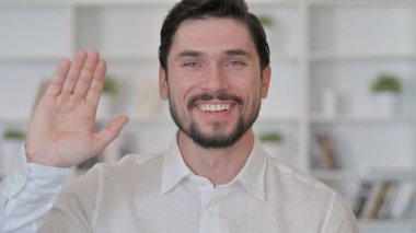 Neşeli genç adam el sallıyor. Merhaba. 