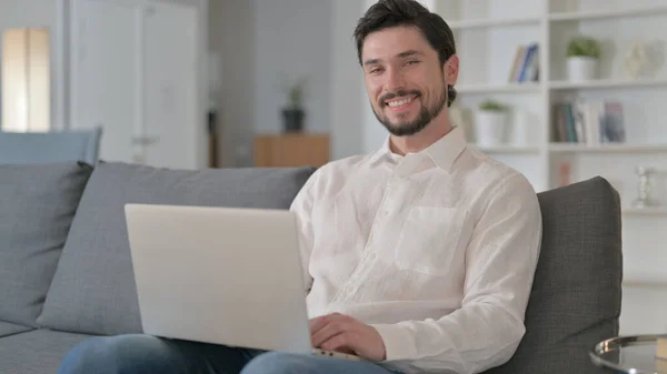 Aantrekkelijke jongeman met laptop glimlachend naar de camera — Stockfoto