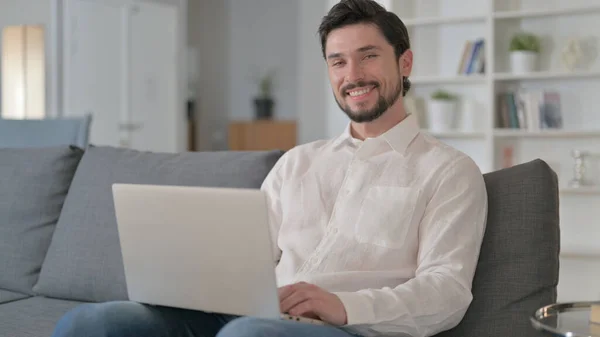 Attraente giovane uomo con computer portatile sorridente alla fotocamera — Foto Stock