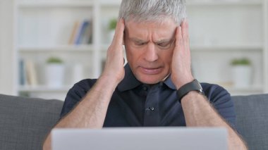 Dizüstü bilgisayarı olan orta yaşlı adamın başı ağrıyor. 