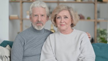 Oturan ve Kameraya Bakan Yaşlı Çift