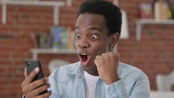 Mladý africký muž slaví na smartphonu — Stock fotografie