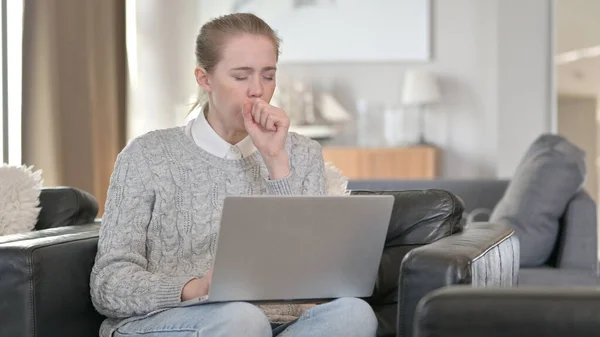 Atrakcyjna kobieta z kaszlem na laptopa w domu — Zdjęcie stockowe