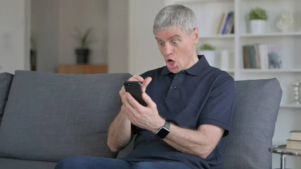 Mann mittleren Alters verliert Smartphone auf Sofa — Stockfoto
