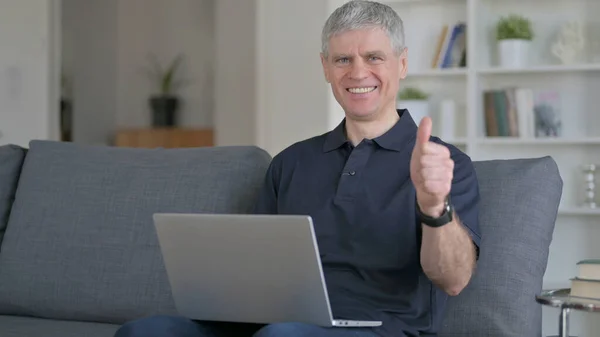 Fröhlicher Mann mittleren Alters mit Laptop macht Daumen hoch — Stockfoto