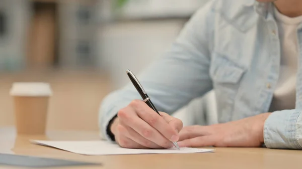 Primer plano de un joven escribiendo en papel —  Fotos de Stock