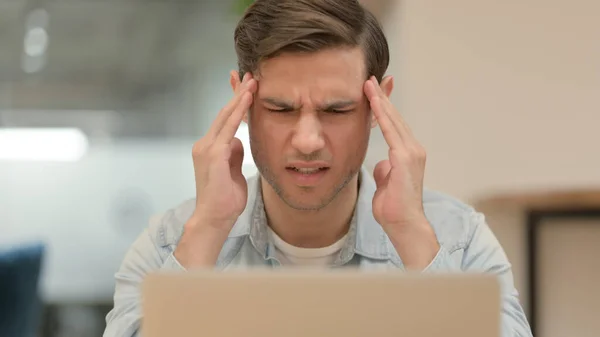 Nahaufnahme eines jungen Mannes mit Laptop, der Kopfschmerzen hat — Stockfoto