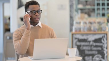 Laptop kullanırken telefonda konuşan Afrikalı Adam 