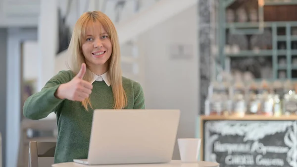 Mulher mostrando polegares para cima assinar enquanto trabalhava no laptop no café — Fotografia de Stock