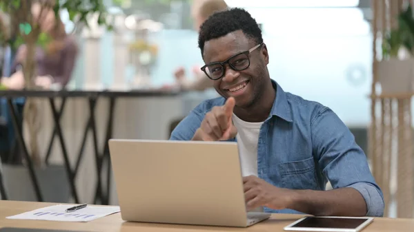 Afrikaner zeigt bei der Arbeit am Laptop auf Kamera — Stockfoto