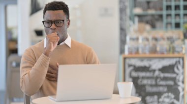 Cafe 'de dizüstü bilgisayar kullanırken öksüren Afrikalı Adam 