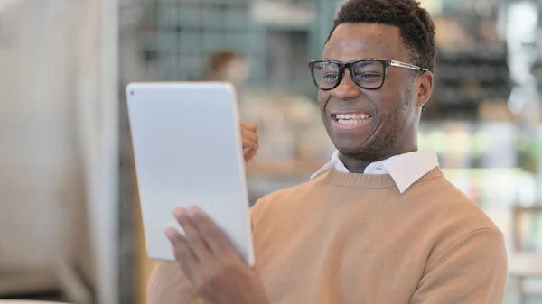 Úspěšný africký muž slaví na tabletu v kavárně — Stock fotografie