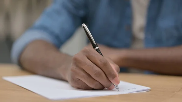 Närbild av afrikansk man som skriver på papper — Stockfoto