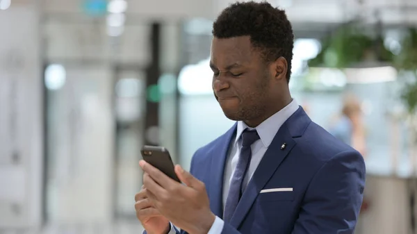 Homme d'affaires africain bouleversé réagissant à la perte sur Smartphone — Photo